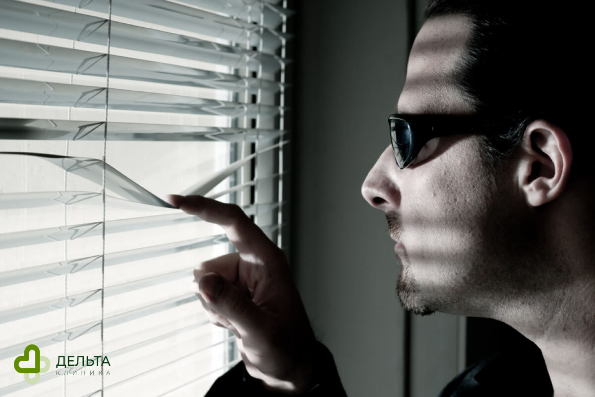 Мужчина смотрит через жалюзи